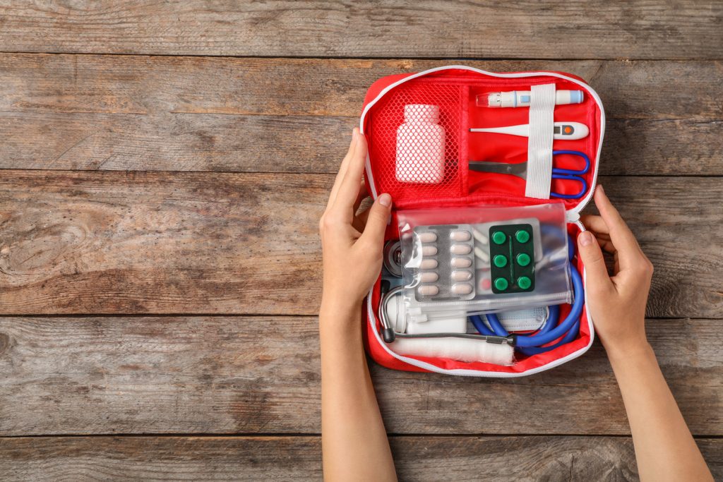 Woman holding first aid kit on wooden background.