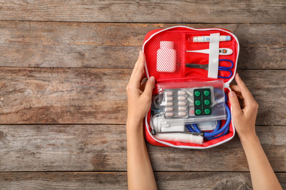 Woman holding first aid kit on wooden background.