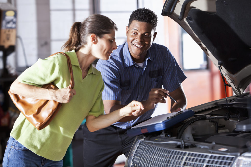 Mechanic and customer looking under the hood of a vehicle